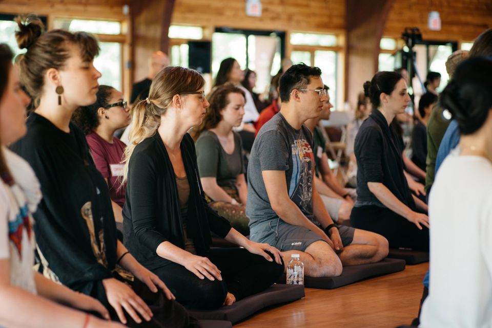 image of young people meditating with their eyes closed in a meditation hall
