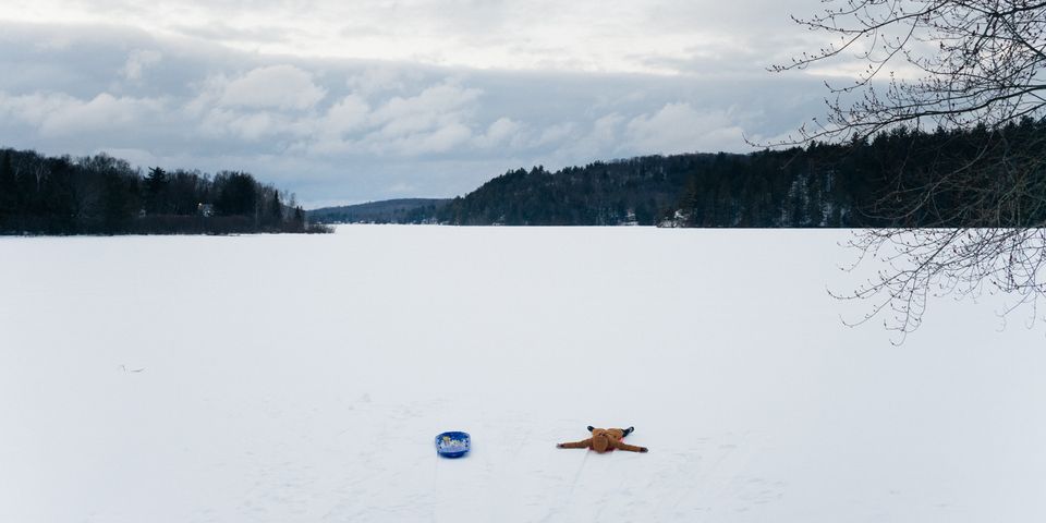 Image of a snow covered lake with a person lying on a red sled